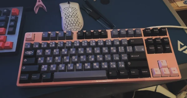 Pink mechanical keyboard with dark keycaps, Japanese legends, and pink arrow keys.