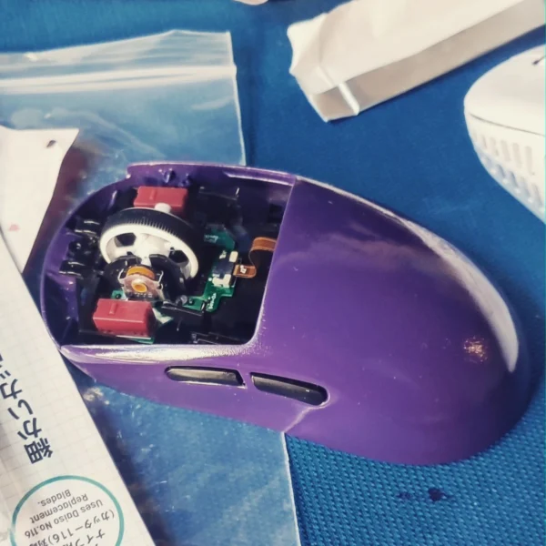 Purple mouse shell with the scroll wheel, switches, and circuit board exposed.