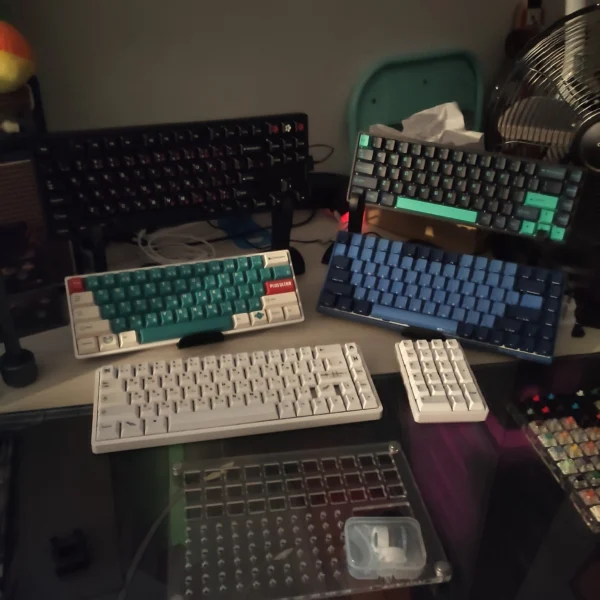Several mechanical keyboards and a separate white number pad displayed on a desk.