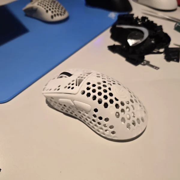 White gaming mouse with a honeycomb shell and two side buttons.